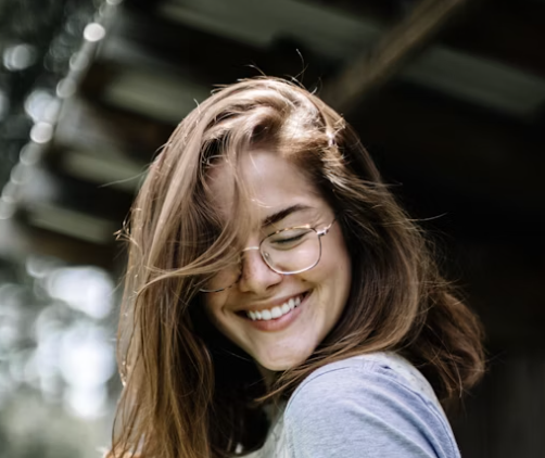 Smiling woman with glasses and long hair outdoors