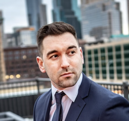 Man in a suit standing outdoors with city buildings behind